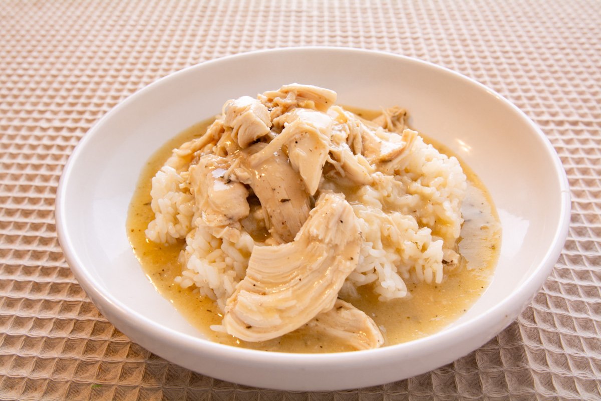 A bowl of rice covered with chicken and gravy