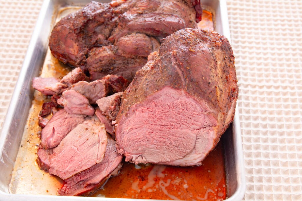 Cooked roast of lamb, sliced showing it is medium rare.